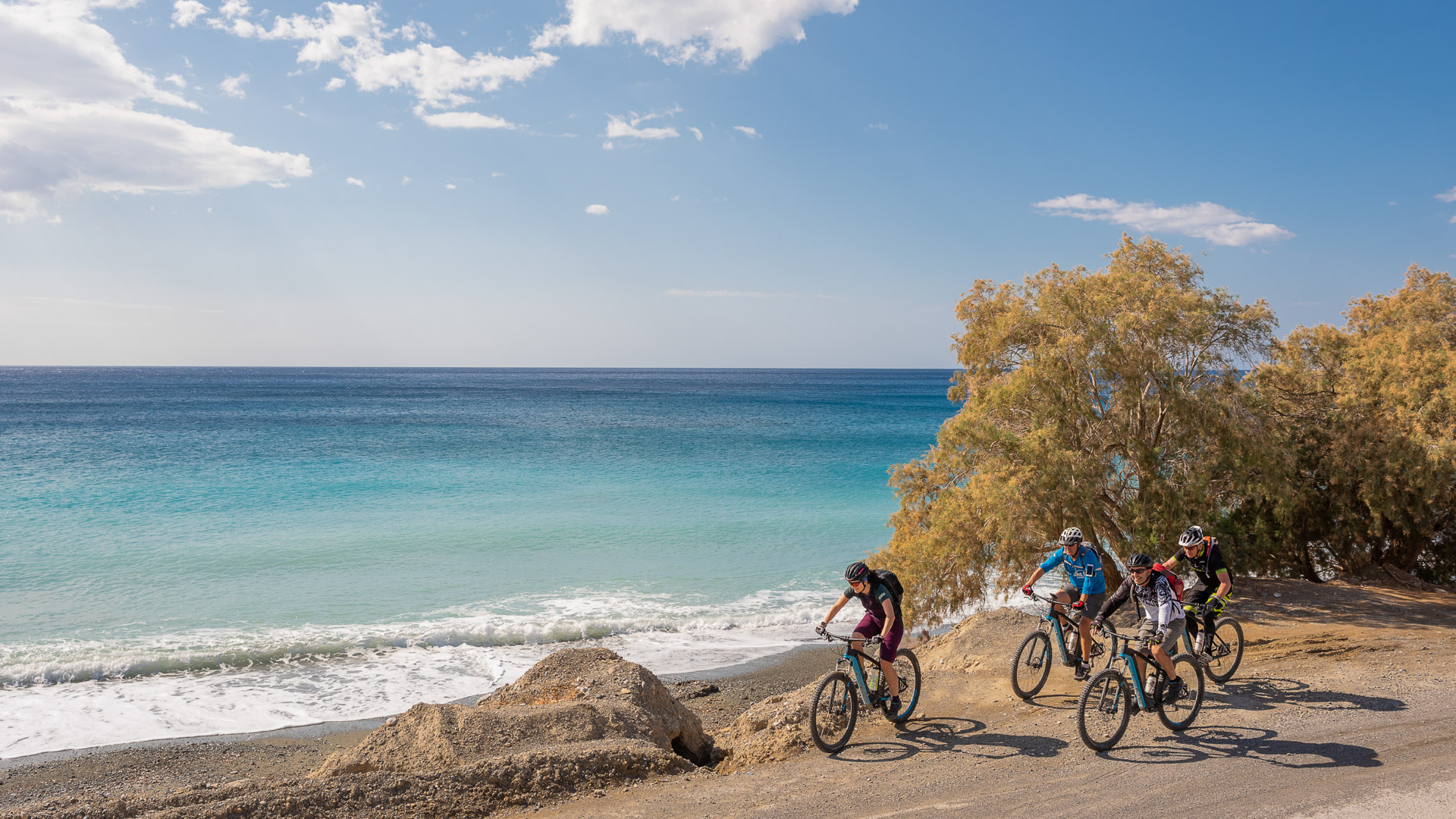 mountain bikers ride on a cretan beach