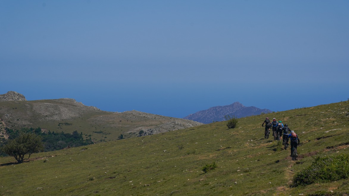 A group of mountainbikers descending a single track towards Collioure, in front of the Med Sea.