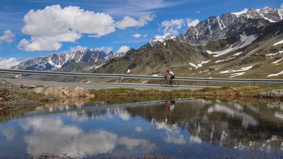 cyclist riding along the lake of Great Saint Bernard pass