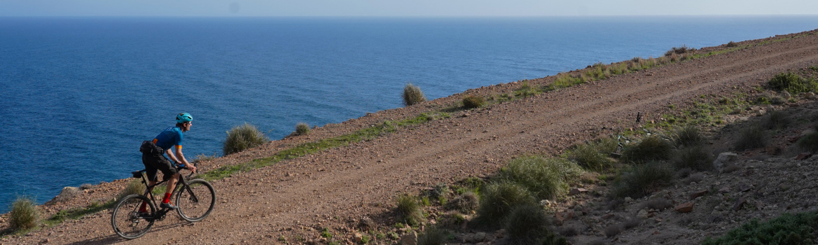 a man by gravelbike climb a perfect track near the Mediterranean Sea
